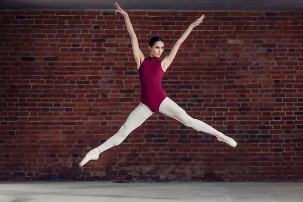 Půvabná tanečnice v červenou kombinézu skákat do vzduchu — Stock fotografie