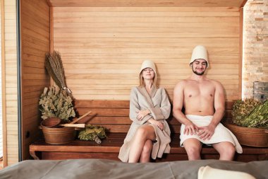Beautiful couple relaxing in sauna and caring about health and skin clipart