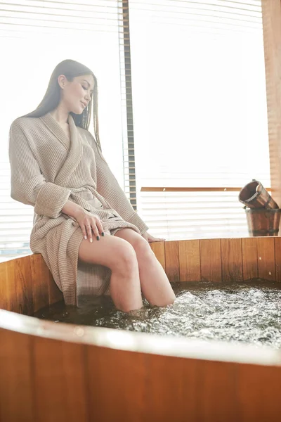 褐发女郎妇女放松在水疗中心的按摩浴缸与全景窗户 — 图库照片