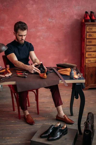 Young attractive cobbler measuring the leather for shoe — Stock Photo, Image