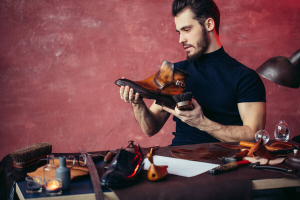 young man cleaning leather boots while sitting on the chair