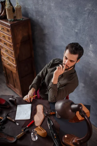 Young clever man making up a new construction of the footwear — Stock Photo, Image