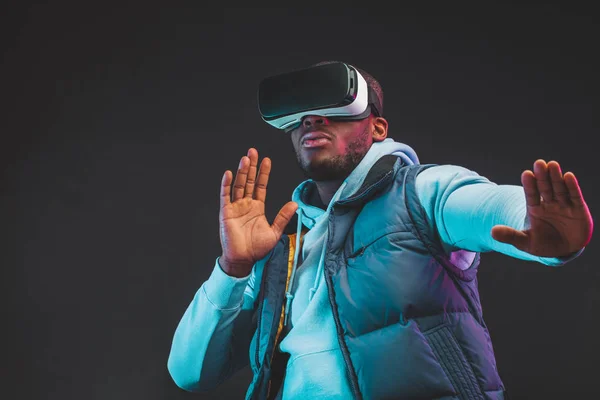 Africano uomo indossare realtà virtuale occhiali isolato su sfondo viola scuro — Foto Stock