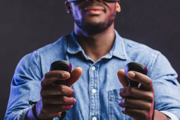 Homem africano vestindo óculos de realidade virtual isolado no fundo roxo escuro — Fotografia de Stock