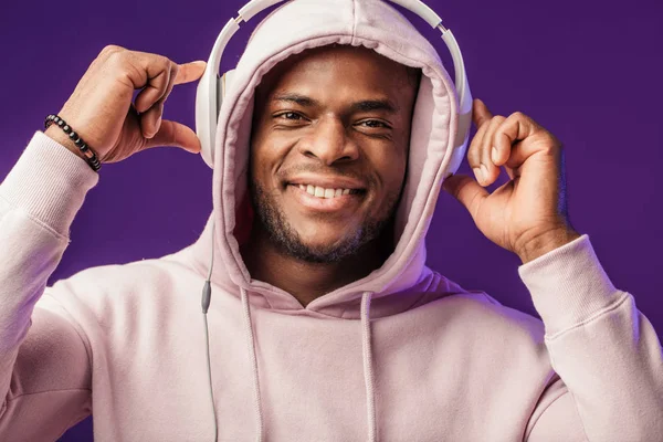 Afrikanischer Mann im Kapuzenpullover mit Kopfhörern, fröhlicher Gesichtsausdruck. Musik, Menschen — Stockfoto