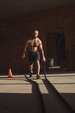 Genç Beyaz adam birlikte savaş ipler bir spor salonunda egzersiz