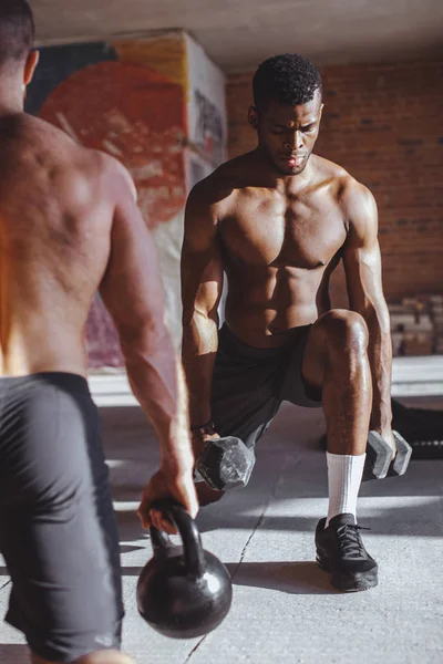 Dos atletas masculinos multirraciales que hacen embestidas con peso en el entrenamiento en interiores —  Fotos de Stock