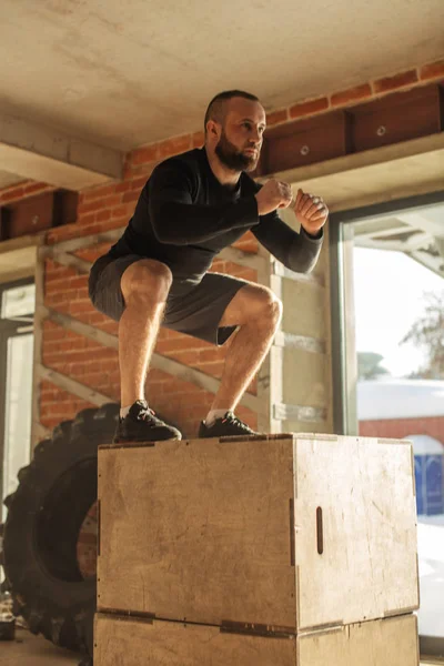 Kaukasiska atletisk man utför plyo box jump motion under crossfit träning — Stockfoto