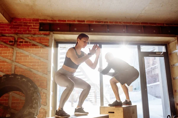 Hombre y mujer saltando tohether en cajas en el gimnasio, entrenamiento funcrional para las personas — Foto de Stock
