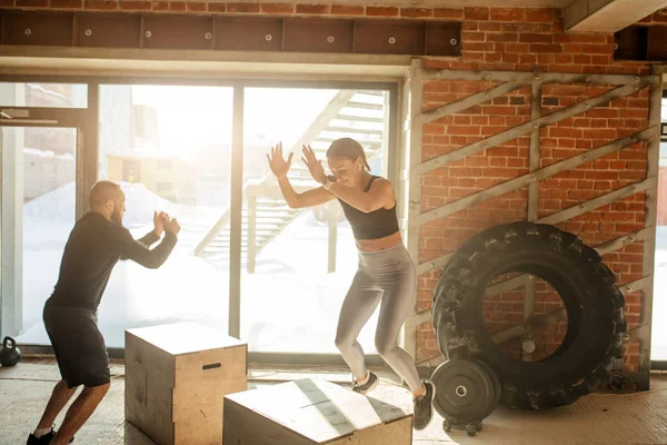 Hombre y mujer saltando tohether en cajas en el gimnasio, entrenamiento funcrional para las personas — Foto de Stock