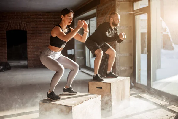 Άνδρας και γυναίκα άλμα tohether σε κουτιά στο γυμναστήριο, προπόνηση funcrional για τους ανθρώπους — Φωτογραφία Αρχείου