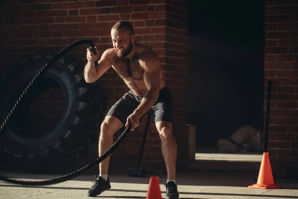 Ung kaukasiska man tränar med slaget rep på ett gym — Stockfoto