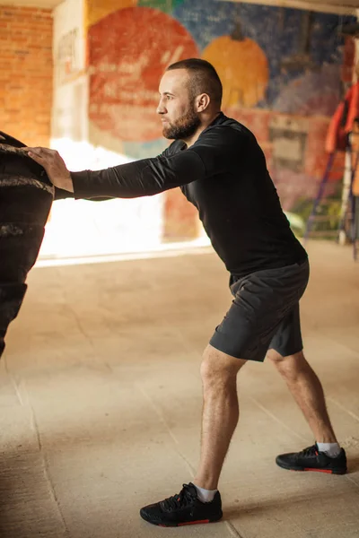 Kaukasische gespierde jongeman wegknippen van zware band in sportschool — Stockfoto