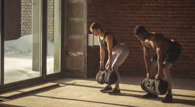 Karışık yarış çift ağız kavgası yaparken egzersiz, ağır kum torbalarının elinde tutarken.