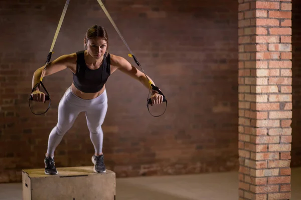 Entrenamiento de mujer fitness en correas TRX en el gimnasio. Estilo Crossfit. Formación TRX . — Foto de Stock