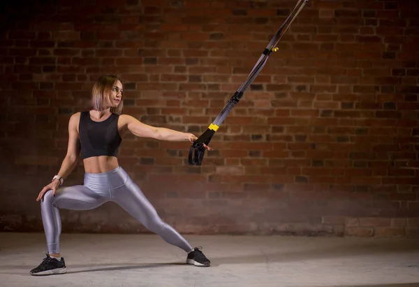 Fitness femme séance d'entraînement sur les sangles TRX dans la salle de gym. Style Crossfit. Formation TRX . — Photo