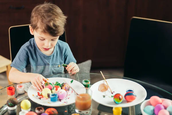 Happy little boy painting Easter eggs, children and creativity