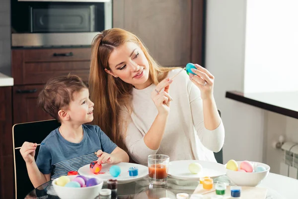 Happy Easter Young mother and her little son painting Easter eggs.