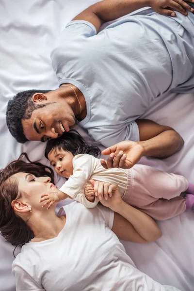 Hija pequeña tocando la cara de su madre mientras descansa en la cama —  Fotos de Stock