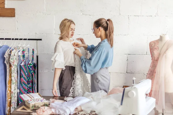 Profissional costureira feminina escolhendo tecido junto com mulher atraente — Fotografia de Stock
