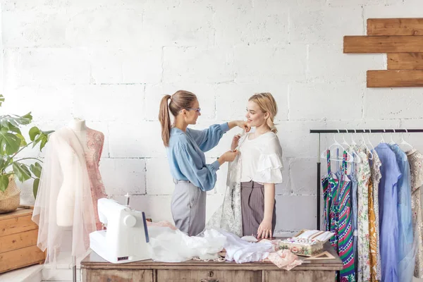 Jovem designer de moda tomando medidas de uma mulher para projetar novo vestido . — Fotografia de Stock