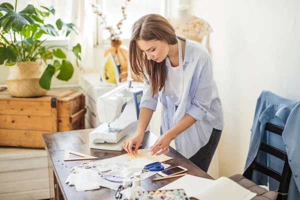 Mooie naaister werkt met een bruiloft jurk model in haar atelier — Stockfoto