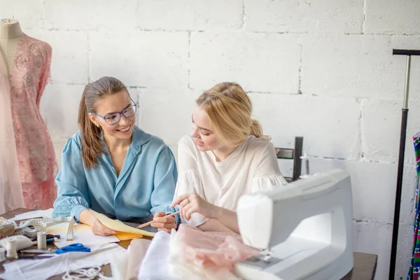 Vrouwelijke naaister ontwerp tonen aan haar cliënt, samen zitten op workshop. — Stockfoto
