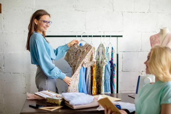 Costurera femenina discutiendo características de la orden con el cliente en acogedor estudio —  Fotos de Stock