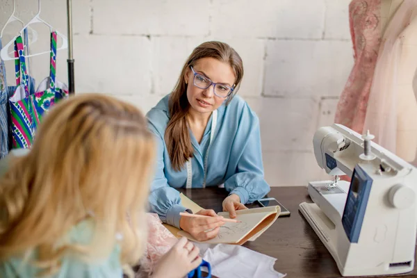 Vrouwelijke naaister bespreken van functies van de bestelling met cliënt in gezellige studio — Stockfoto