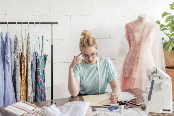 Mode-ontwerper op het werk. Talanted naaister het tekenen van de schets op haar werkruimte — Stockfoto