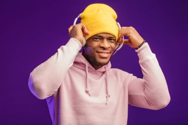 Kapüşonlu ve kulaklıklı Afrikalı bir adam, mutlu bir ifade. Müzik, millet.