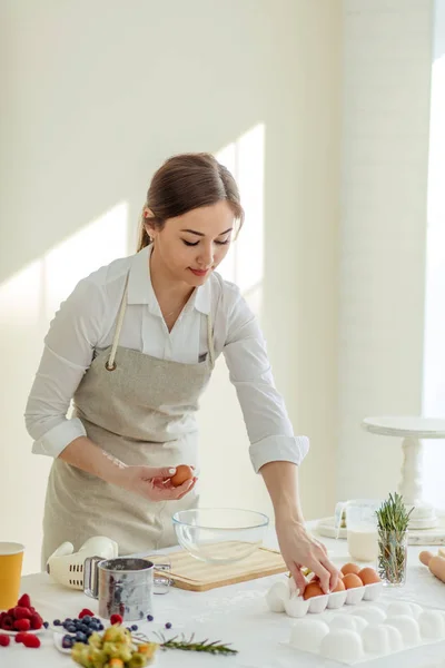 Belle jeune femme au foyer tenant des œufs pour faire le petit déjeuner pour la famille — Photo