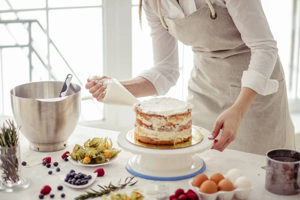 Impresionante confitero apretando crema en la torta en la cocina . —  Fotos de Stock