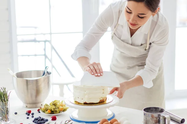 Beautiful woman concentrated on smoothing cake — Stock Photo, Image