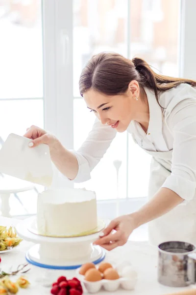 Impresionante chica bonita comprobar el pastel después de suavizarlo —  Fotos de Stock