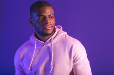 Afrikalı adam spora hazır beyaz kapüşonlu sweatshirt giyiyor mor üzerine izole edilmiş..