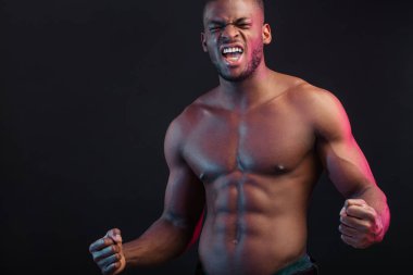 Muhteşem karın kasları ve çıplak gövdesi olan, koyu arkaplanda soyutlanmış Afrikalı bir adam..