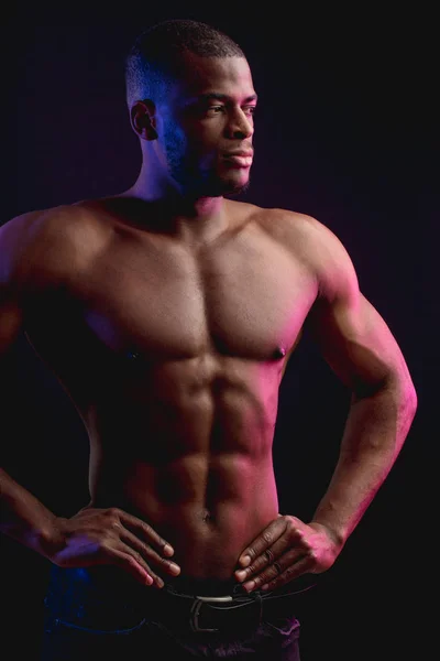 Afrikanischer Sportler mit nacktem Oberkörper posiert vor dunkler Wand. Unauffälliges Foto. — Stockfoto