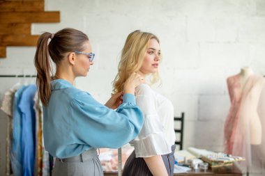Yeni elbise tasarımı için bir kadının ölçümleri alarak genç moda tasarımcısı.