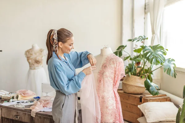 Linda costureira está trabalhando com um modelo de vestido de noiva em seu estúdio — Fotografia de Stock