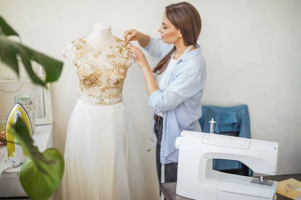 Linda costureira está trabalhando com um modelo de vestido de noiva em seu estúdio — Fotografia de Stock