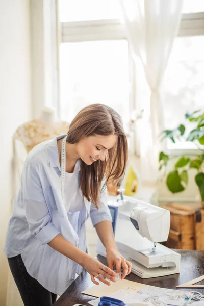 Mooie naaister werkt met een bruiloft jurk model in haar atelier — Stockfoto