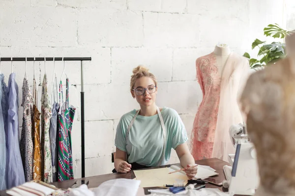 Modedesigner på jobbet. Produkt sömmerska ritning skiss på hennes arbetsyta — Stockfoto