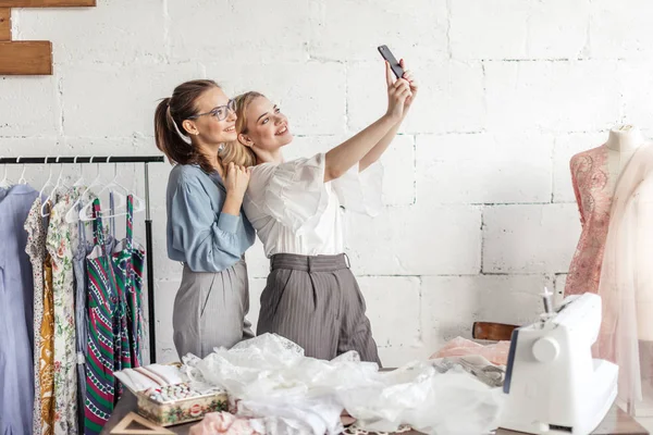 縫製工場でカメラを見て 2 つのかなり若い女性デザイナー. — ストック写真