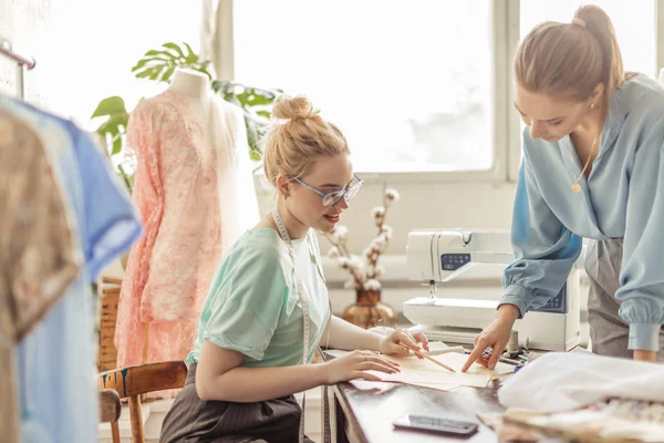 Vrouwelijke naaister bespreken van functies van de bestelling met cliënt in gezellige studio — Stockfoto