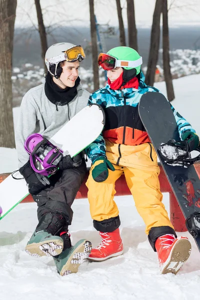 Dos amantes snowboarders amorosos descansando en la cima de la pista de esquí —  Fotos de Stock