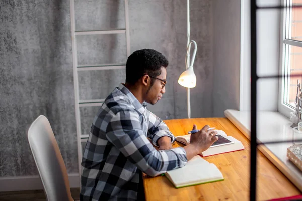 Aantrekkelijke Afro student zitten aan de tafel en de voorbereiding op de examens — Stockfoto