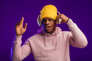 Kapüşonlu ve kulaklıklı Afrikalı bir adam, mutlu bir ifade. Müzik, millet.