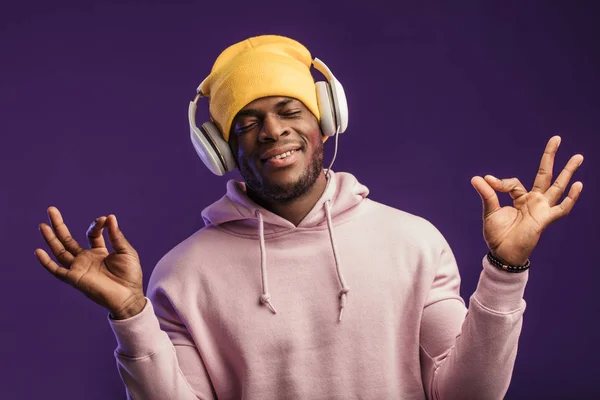 Afrikaanse man in hoodie met hoofdtelefoon geïsoleerd, gelukkige uitdrukking. Muziek, mensen. — Stockfoto