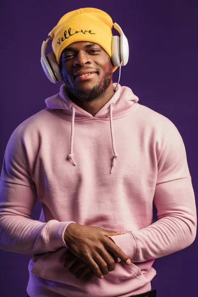 Homme africain en sweat à capuche avec écouteurs isolés, expression heureuse. Musique, gens — Photo